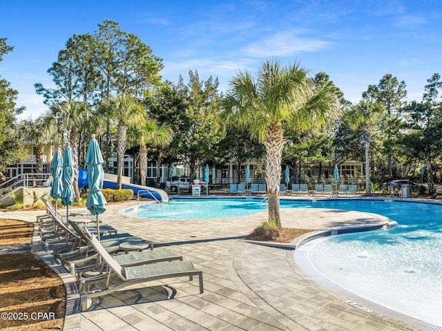 community pool featuring a patio area and a water slide