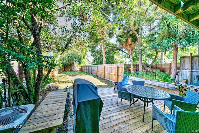 wooden terrace with a fenced backyard and area for grilling