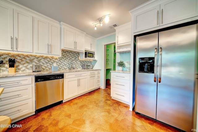 kitchen with stainless steel appliances, white cabinetry, backsplash, light stone countertops, and light floors