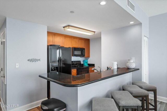 15625 Front Beach Rd Unit 1405, Panama City Beach, FL 32413 - kitchen featuring dark countertops, a breakfast bar area, baseboards, visible vents, and black appliances