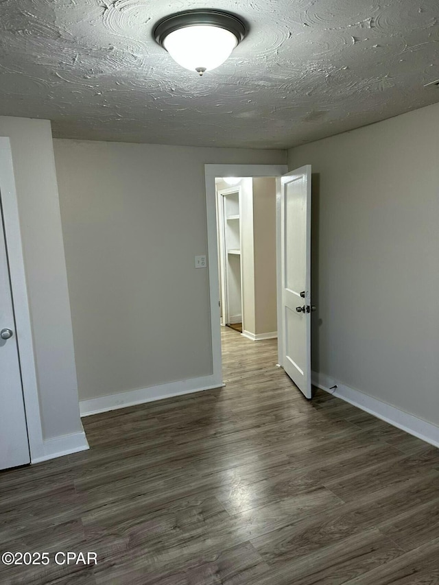 spare room with baseboards, wood finished floors, and a textured ceiling