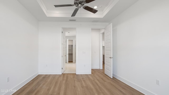 unfurnished bedroom featuring baseboards, a raised ceiling, and light wood finished floors