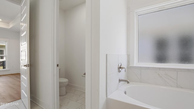 bathroom with baseboards, a garden tub, toilet, and marble finish floor