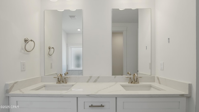 bathroom with double vanity, visible vents, and a sink