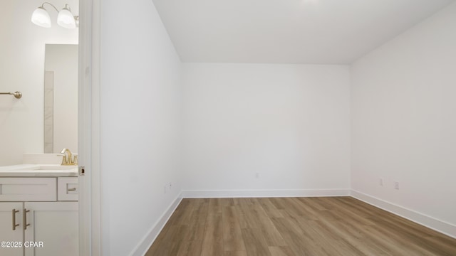 interior space with light wood-style floors, a sink, and baseboards