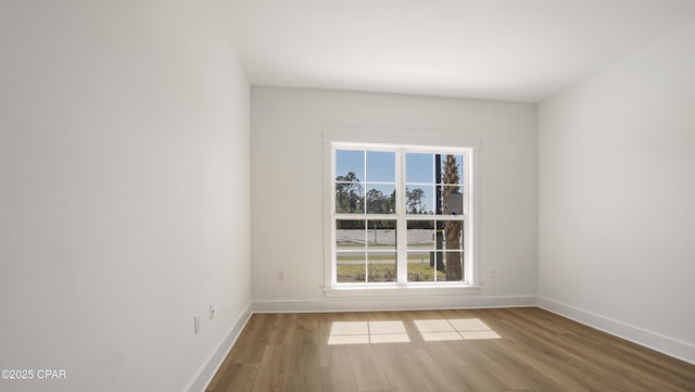 empty room with baseboards, a wealth of natural light, and wood finished floors