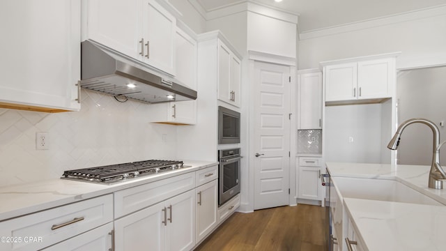 kitchen with backsplash, a sink, under cabinet range hood, stainless steel appliances, and white cabinetry