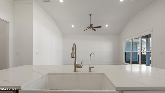 kitchen featuring a sink, light stone countertops, a ceiling fan, and lofted ceiling