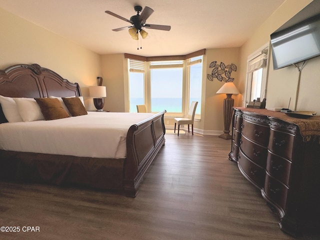 bedroom featuring baseboards, a ceiling fan, a water view, and dark wood-style floors
