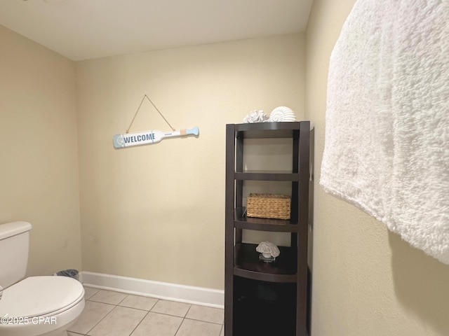bathroom with tile patterned flooring, baseboards, and toilet