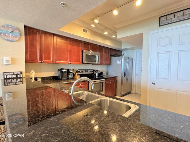 kitchen with visible vents, a sink, track lighting, dark stone counters, and stainless steel appliances