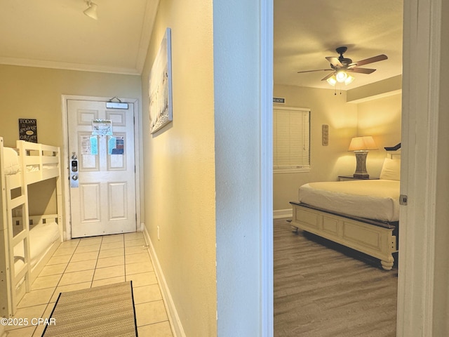 hall featuring baseboards, ornamental molding, and light tile patterned flooring