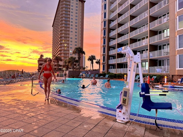 pool at dusk featuring a community pool