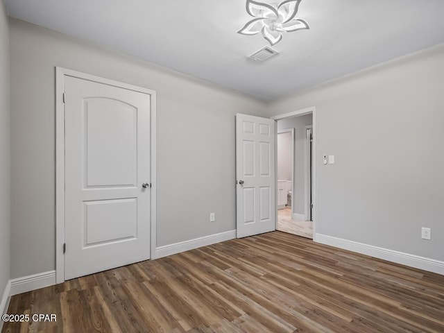 unfurnished bedroom featuring visible vents, wood finished floors, and baseboards
