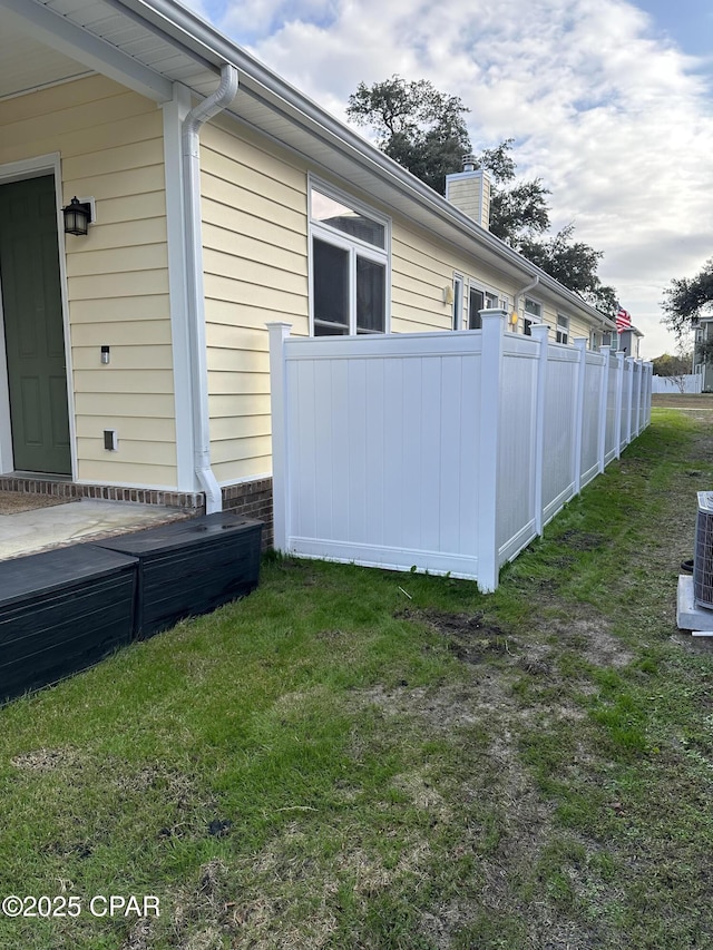 view of property exterior featuring a chimney, fence, cooling unit, and a yard