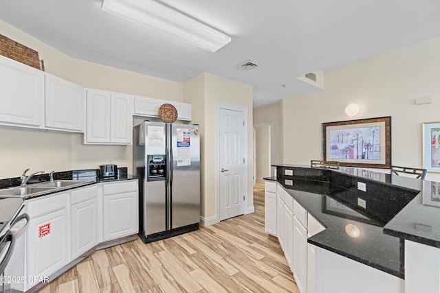 15817 Front Beach Rd Unit I-2309, Panama City Beach, FL 32413 - kitchen with stainless steel fridge, white cabinets, light wood-style flooring, dark stone counters, and stove
