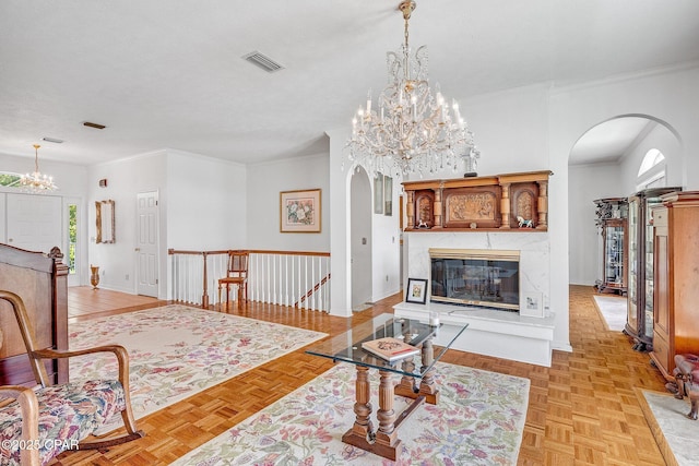living area featuring a premium fireplace, arched walkways, a chandelier, and visible vents
