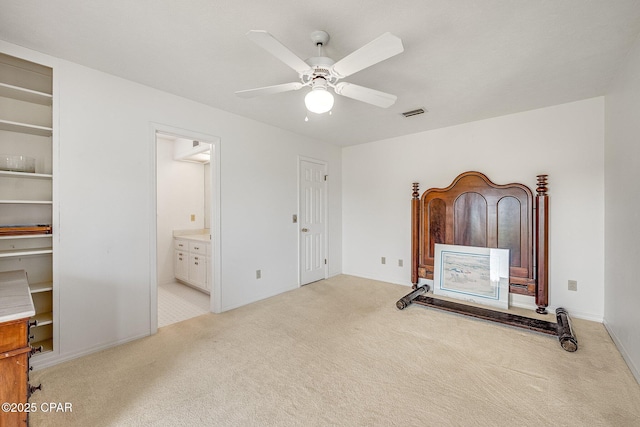 unfurnished bedroom featuring visible vents, light carpet, baseboards, ensuite bathroom, and ceiling fan