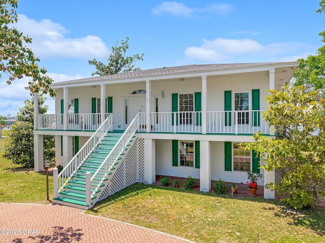 view of front facade featuring stairs, a front lawn, stucco siding, and covered porch