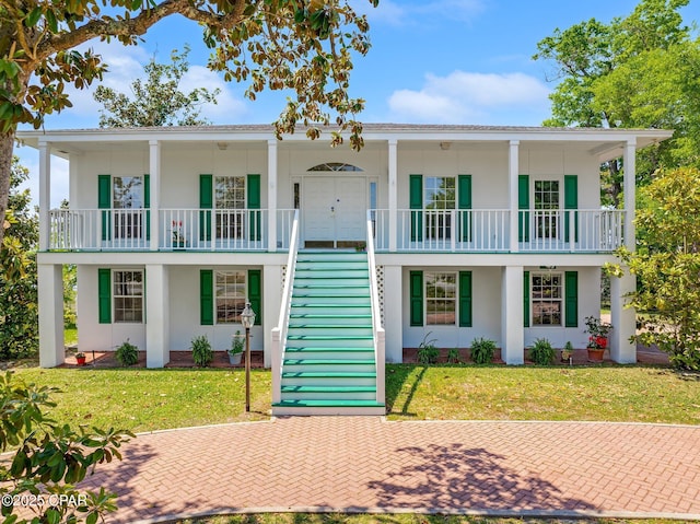 view of front facade with stucco siding, a front yard, and stairway