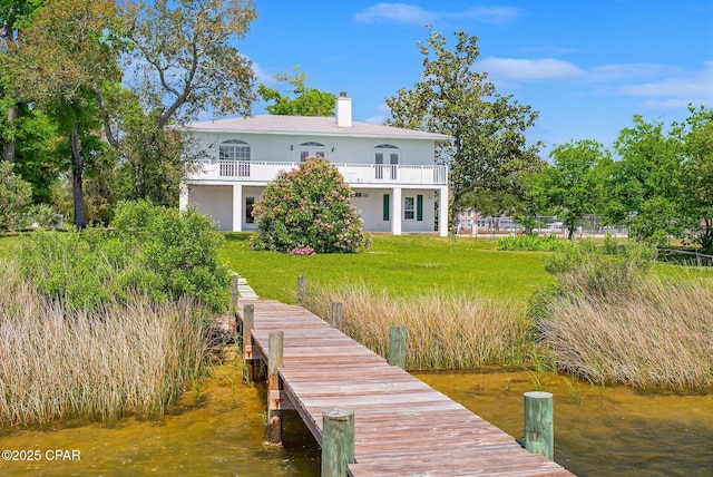 rear view of house featuring a water view, a yard, a balcony, and a chimney