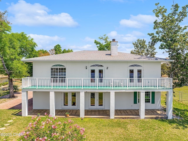 back of house with french doors, stucco siding, and a lawn