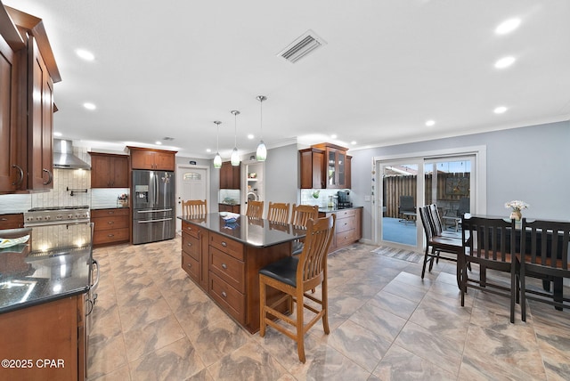 kitchen featuring wall chimney exhaust hood, visible vents, backsplash, ornamental molding, and appliances with stainless steel finishes