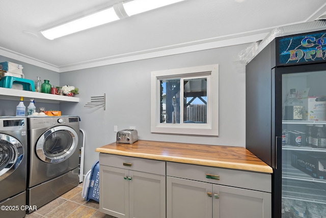 clothes washing area with cabinet space, washing machine and clothes dryer, and ornamental molding