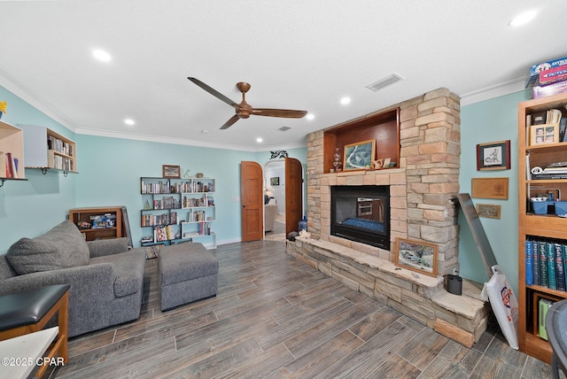 living room with a fireplace, visible vents, a ceiling fan, and crown molding