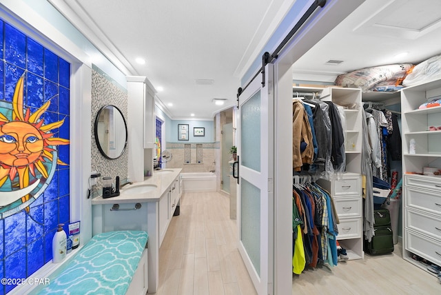 full bathroom featuring a garden tub, wood finished floors, a spacious closet, and vanity