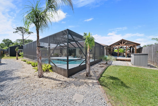 pool with fence, a lawn, glass enclosure, and a gazebo