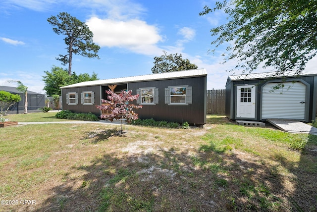 view of front of property featuring fence, an outbuilding, a front yard, and metal roof
