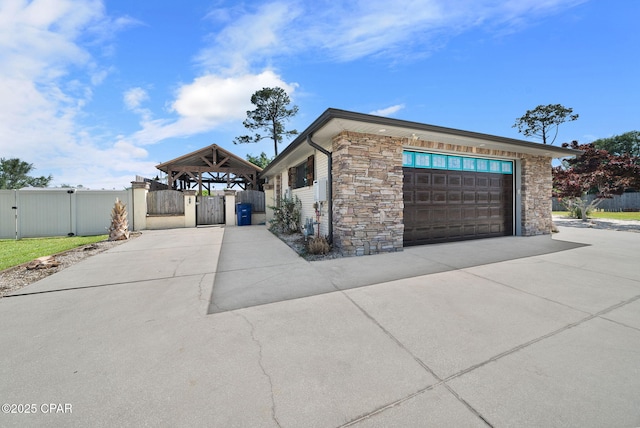 view of front facade featuring a gate, fence, a garage, driveway, and stone siding