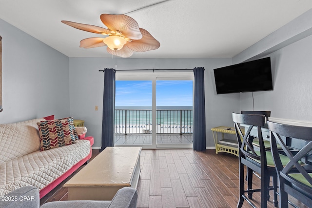 living area with a ceiling fan, baseboards, and wood finished floors