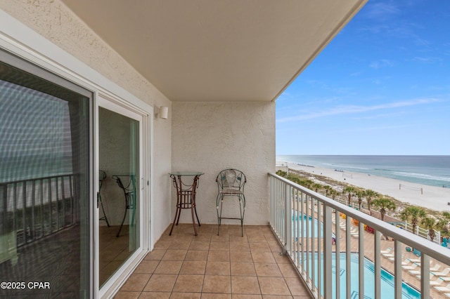 balcony with a water view and a view of the beach