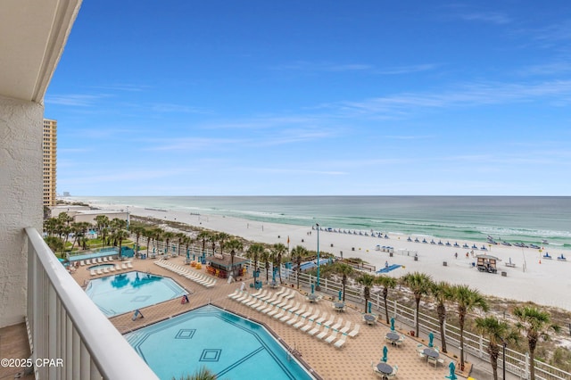 community pool featuring a hot tub, a beach view, and a water view