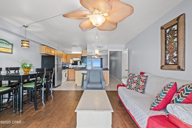 living area with ceiling fan, visible vents, and light wood-style flooring