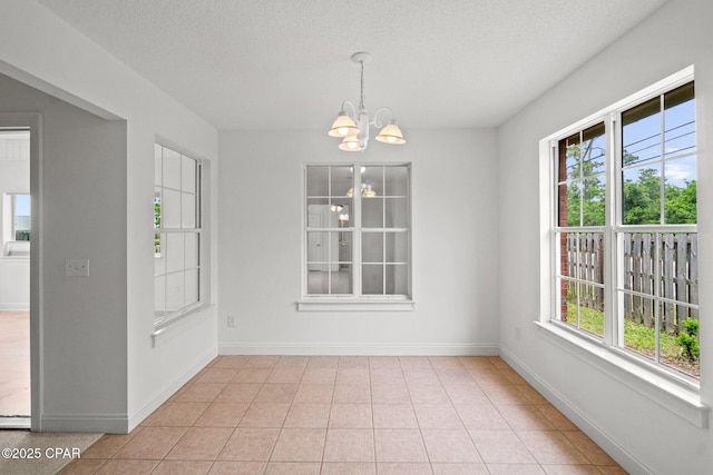 unfurnished dining area with a textured ceiling, plenty of natural light, and a notable chandelier