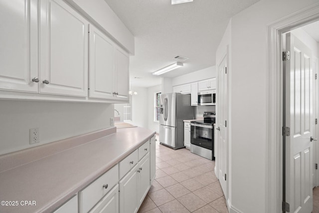 kitchen with light tile patterned floors, white cabinets, appliances with stainless steel finishes, visible vents, and light countertops