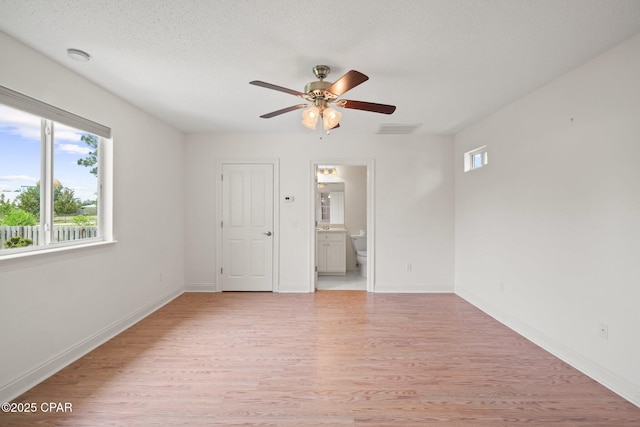 unfurnished room with a textured ceiling, visible vents, ceiling fan, baseboards, and light wood finished floors