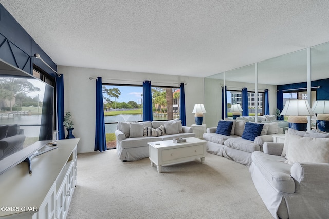 living area featuring a wealth of natural light, light carpet, a textured ceiling, and a water view