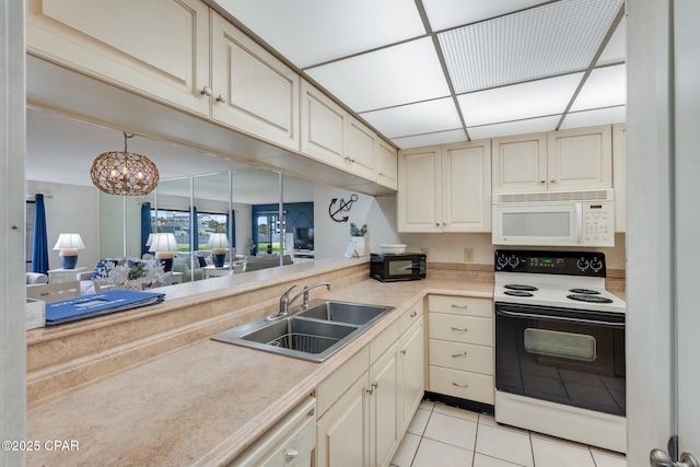 kitchen featuring a sink, light countertops, cream cabinetry, electric range, and white microwave
