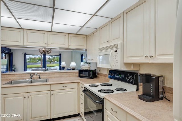 kitchen featuring a sink, range with electric cooktop, black microwave, white microwave, and light countertops