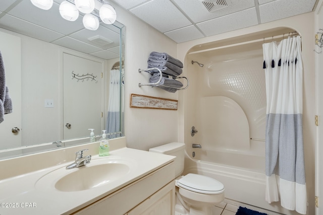 bathroom featuring a paneled ceiling, vanity, shower / bath combo with shower curtain, toilet, and visible vents