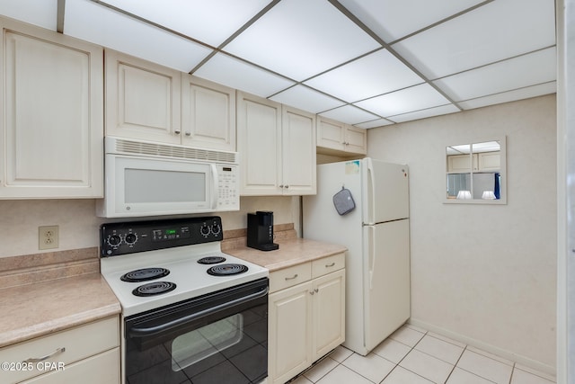 kitchen with white appliances, cream cabinets, light tile patterned floors, light countertops, and baseboards