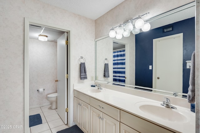 full bath featuring toilet, tile patterned flooring, double vanity, and a sink