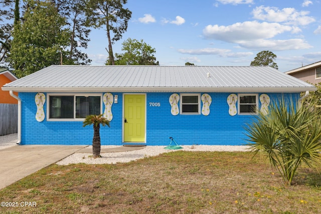 single story home featuring brick siding, metal roof, and a front yard