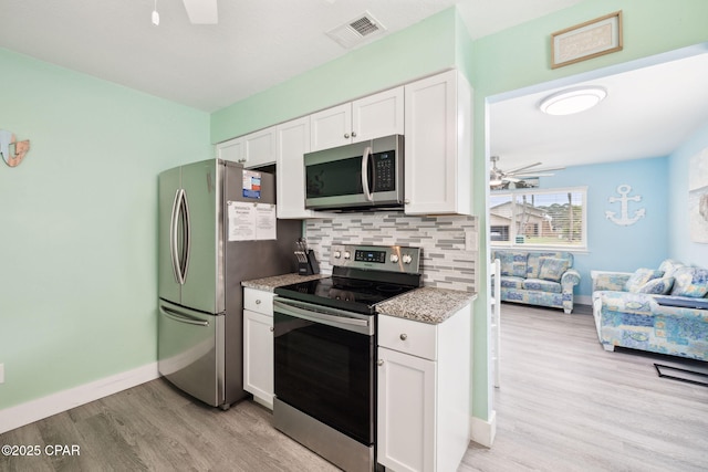 kitchen featuring ceiling fan, visible vents, baseboards, light wood-style floors, and stainless steel appliances
