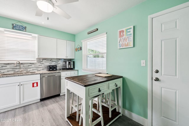 kitchen featuring white cabinets, a sink, dishwasher, light wood-type flooring, and backsplash