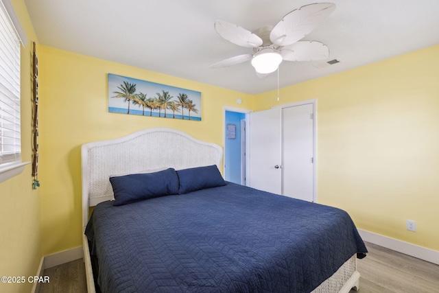 bedroom with baseboards, wood finished floors, and visible vents